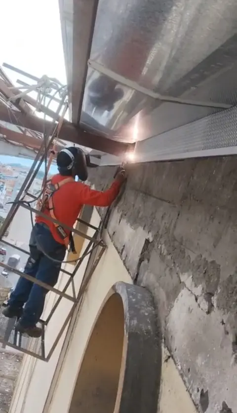 Soldador con arnés trabajando en fachada